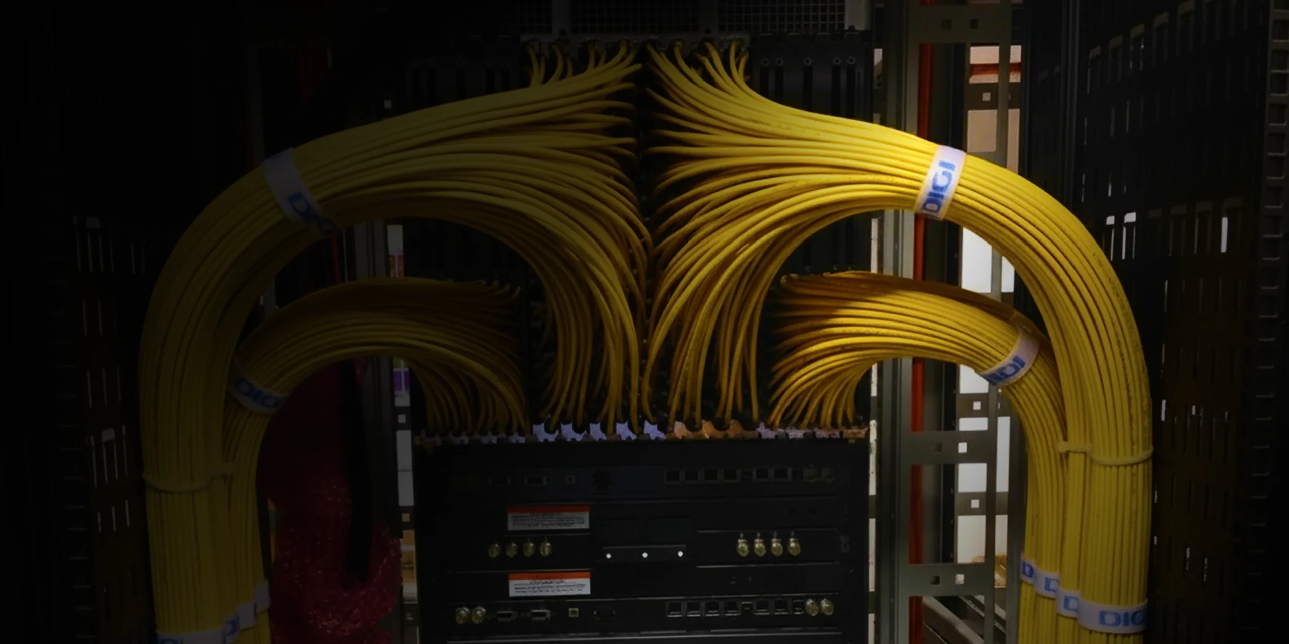 Network server rack with neatly organized yellow fiber optic cables connecting to equipment, showcasing efficient data management and connectivity in a data center environment.